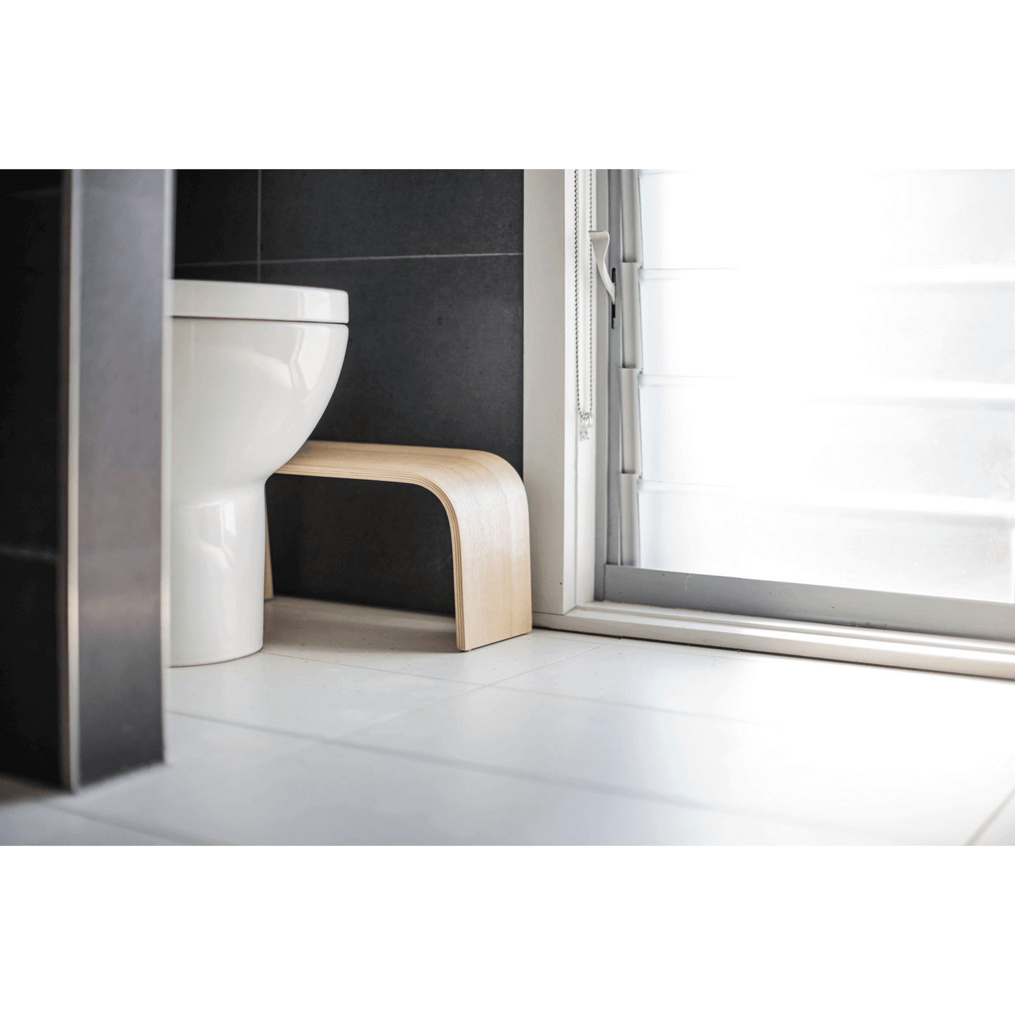 The PROPPR Timber - Tasmanian Oak Toilet Foot Stool - side view in a bathroom beside a toilet