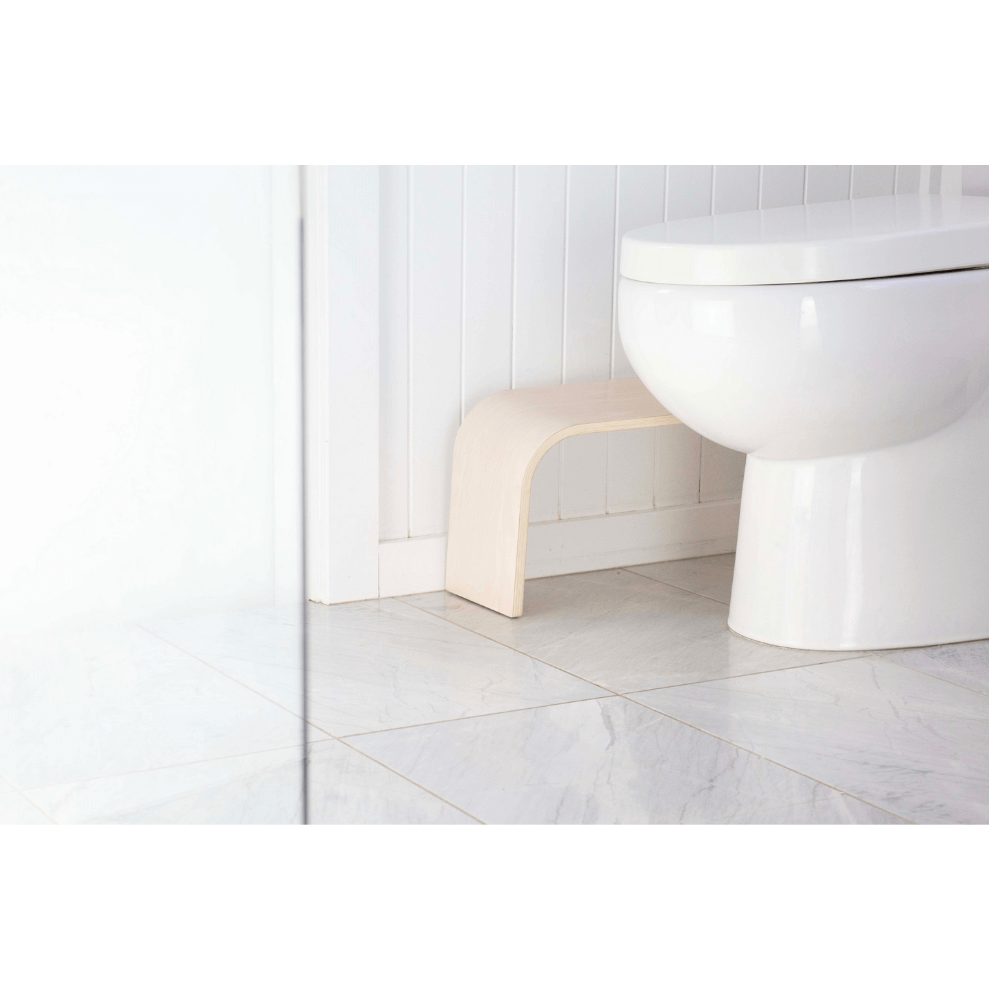 The PROPPR Timber - Whitewash Toilet Foot Stool - side view in a bathroom beside a toilet